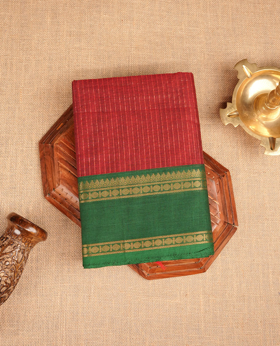 Maroon colour chettinad cotton featuring gold zari check pattern on body , complemented by contrast Green colour with gold zari border, paired with matching blouse piece.