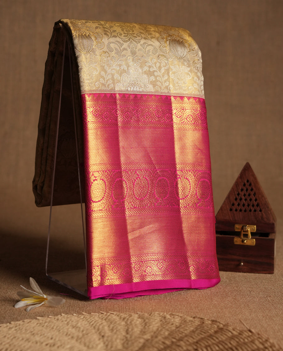 Golden Colour Kancheepuram tissue silk saree adorned with intricate silver and gold zari floral jaal work on the body, enhanced by a contrasting traditional floral kodi design border, paired with a matching blouse.