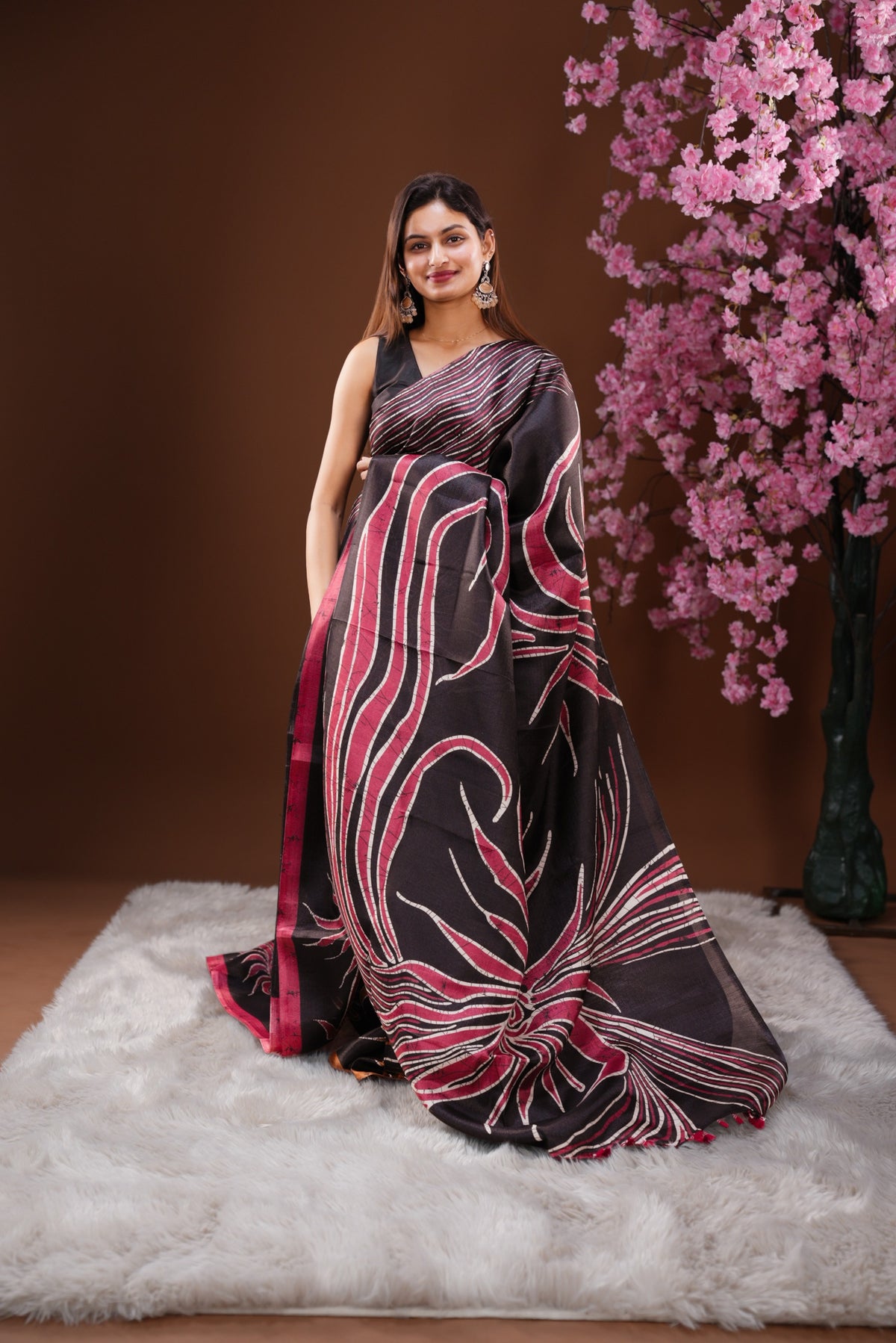 Black colour Semi Khadi Silk Saree featuring a plain black body, complemented by a peach colour geometric pattern on border and paired with a matching blouse piece.