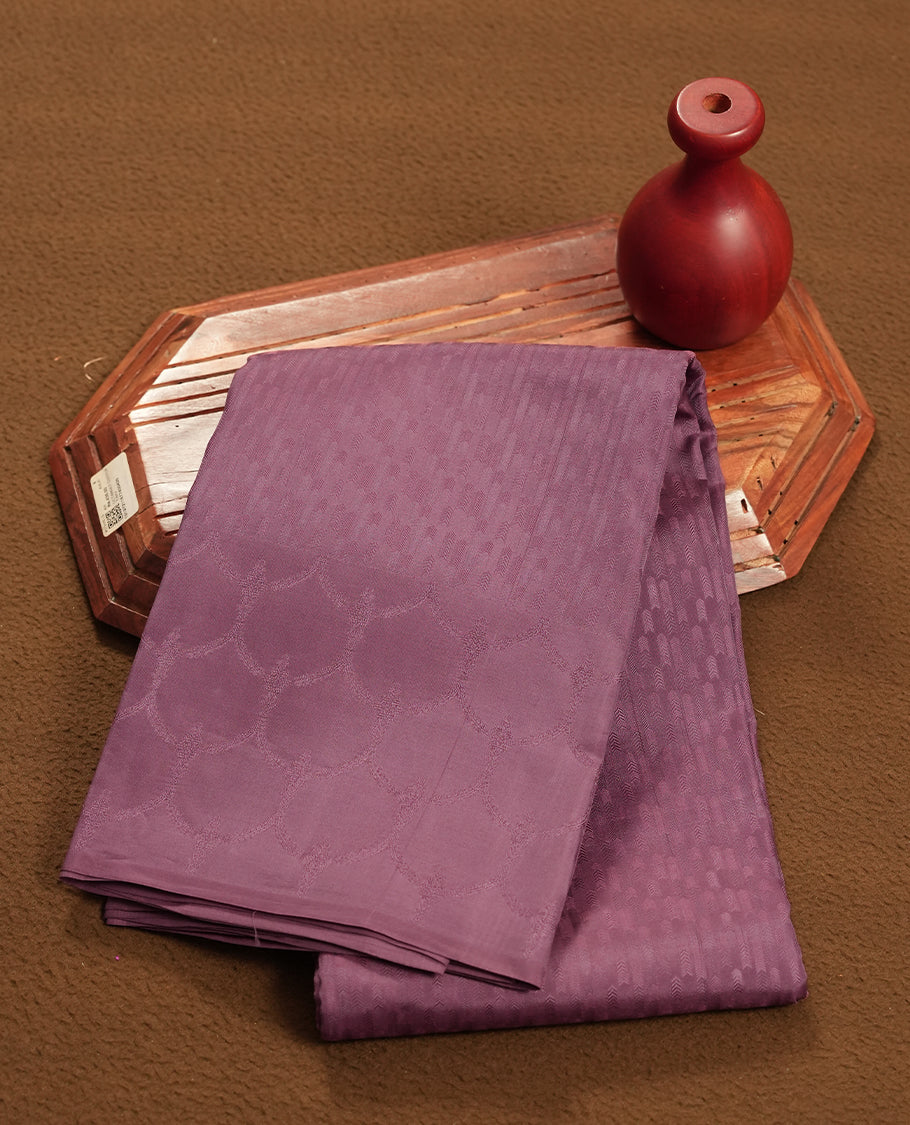 Dark mauve colour semi soft silk saree featuring a self coloured textured patterned body, complemented by self coloured motifes on pallu & border and a matching blouse piece.