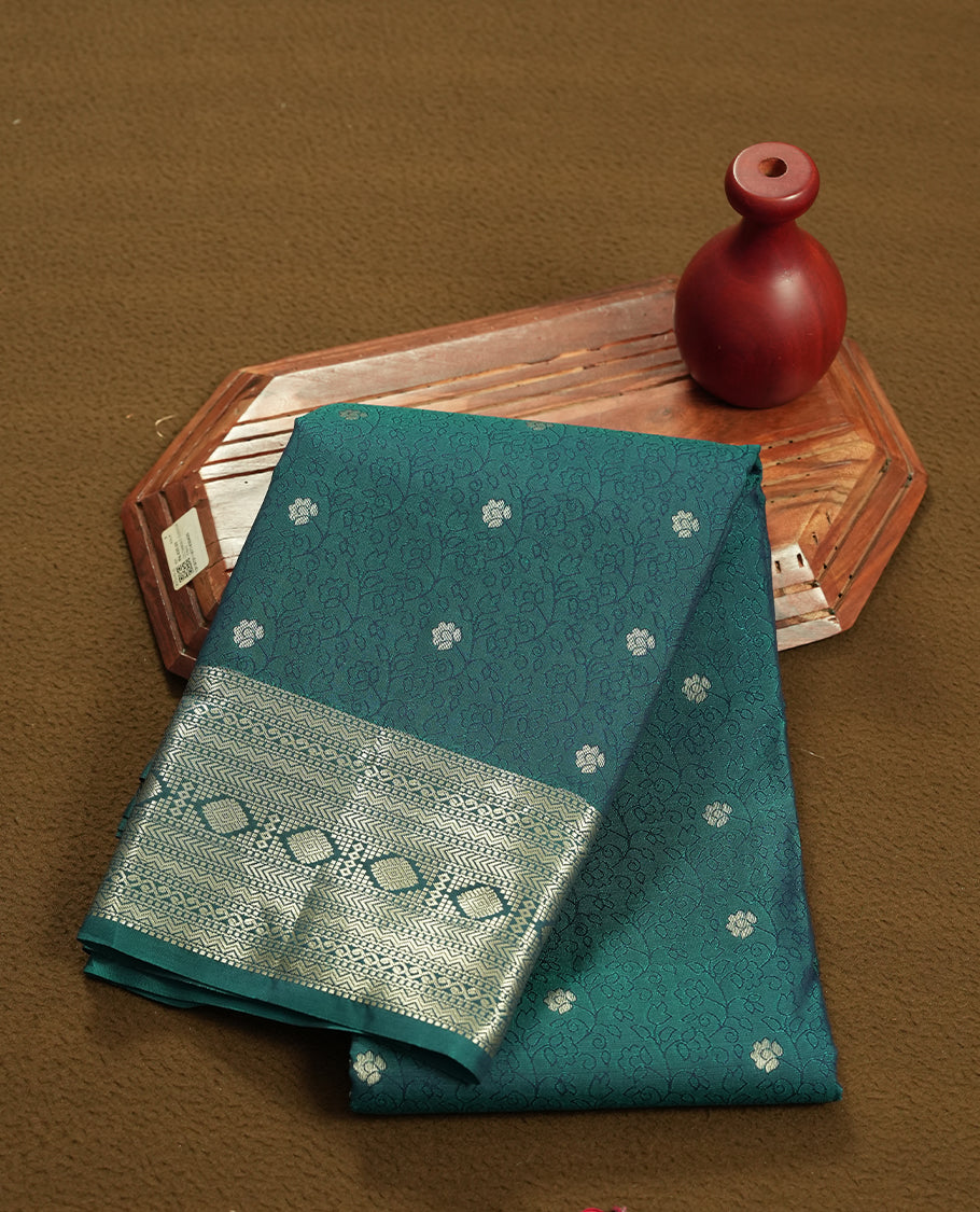 Teal Green colour semi soft silk saree featuring a self coloured textured with golden patterned body, complemented by self coloured golden zari motifes on pallu & border and a matching blouse piece.
