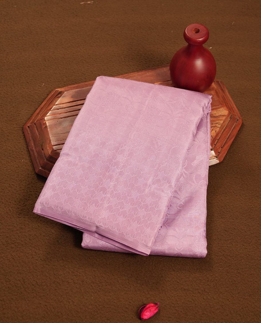 dusty lavender colour semi soft silk saree featuring a self coloured textured patterned body, complemented by self coloured pallu & border and a matching blouse piece.