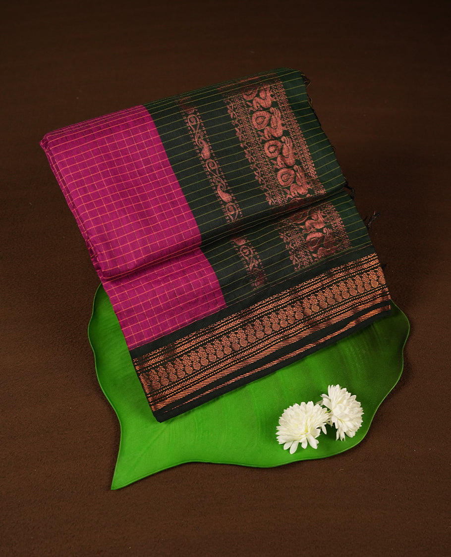 Magenta purple coloured mixed Kalyani cotton saree featuring copper zari checks on the body, complemented by a dark green coloured border and pallu adorned with copper zari patterns, Paired with a matching blouse.