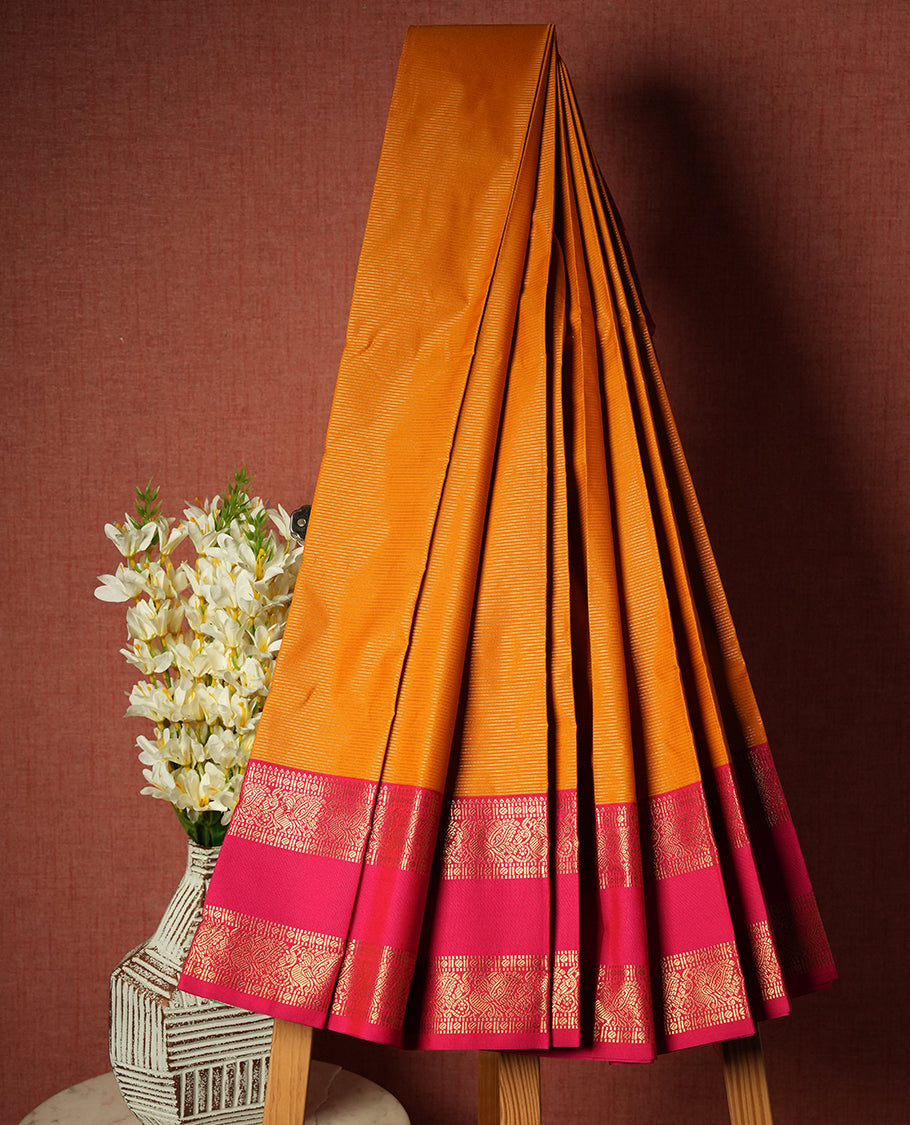 Harvest gold colour Semi Silk Saree with gold zari striped patterns on the body, paired with a contrasting rani pink colour traditional pallu and border, and a matching blouse piece.