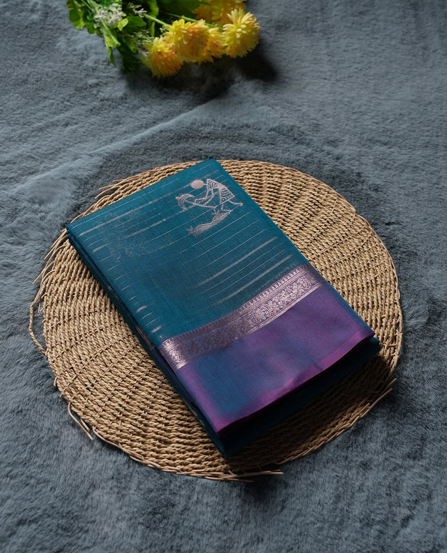 Teal Green colour Silk Cotton Saree with Silver Warli Motifs and Fine Stripes on the Body, Contrasting Silver Zari Pallu Featuring Allover Geometric Pattern and Warli Procession Border, Finished with a Purple Selvedge and Coordinated Blouse Piece