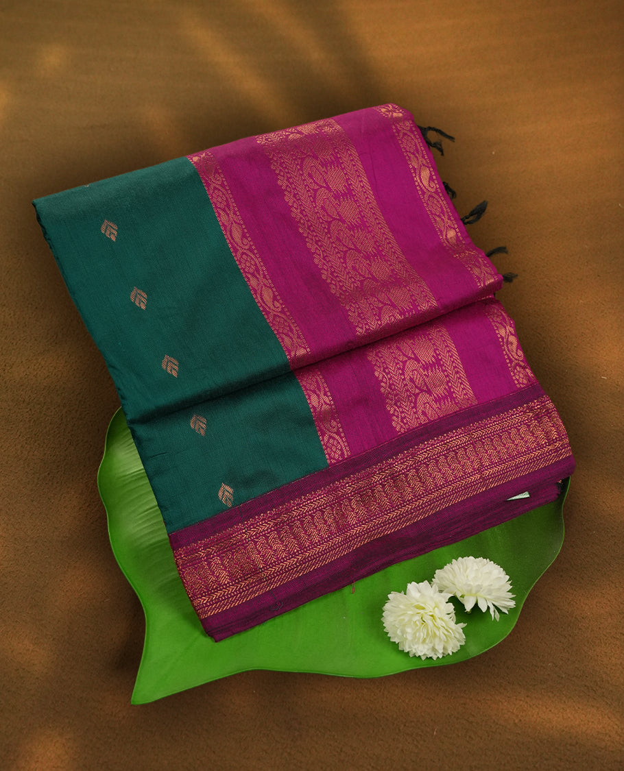Deep Green colour Kalyani Cotton saree with golden motifs, paired with a contrasting magenta border featuring intricate zari work & Comes with a matching blouse piece.