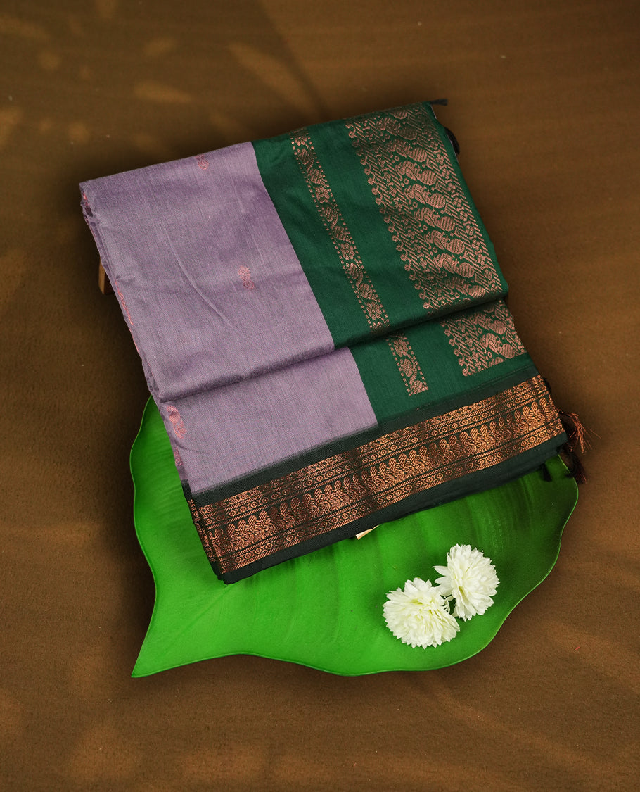 Soft Lavender colour Kalyani Cotton saree with delicate woven zari buttas all over, paired with a contrasting deep bottle green border and pallu intricately woven with rich copper zari & Comes with a matching blouse piece.