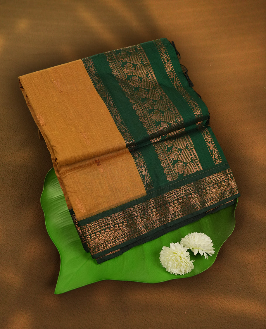 Mustard yellow colour Kalyani Cotton saree with rich green border and pallu, featuring copper zari motifs and intricate weaving & Includes a matching blouse piece.