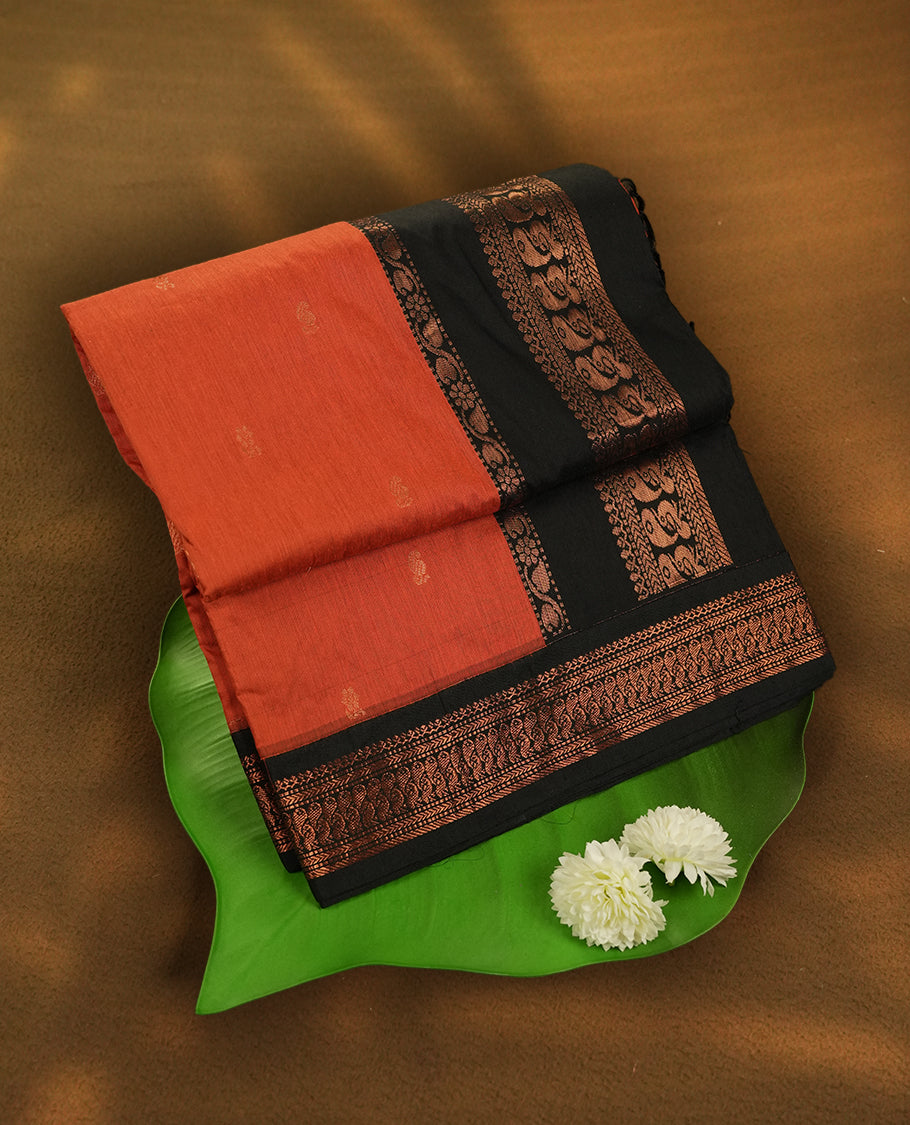 Orange colour Kalyani Cotton saree with rich black colour border with peacock motifs on pallu, featuring copper zari and intricate weaving & Includes a matching blouse piece.