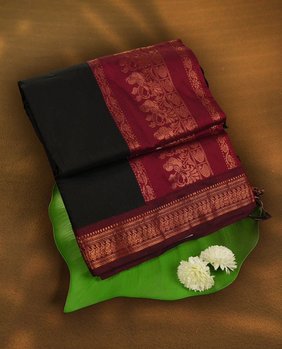 Black colour Kalyani Cotton saree with rich maroon border and pallu, featuring floral copper zari motifs and intricate weaving & includes a matching blouse piece.
