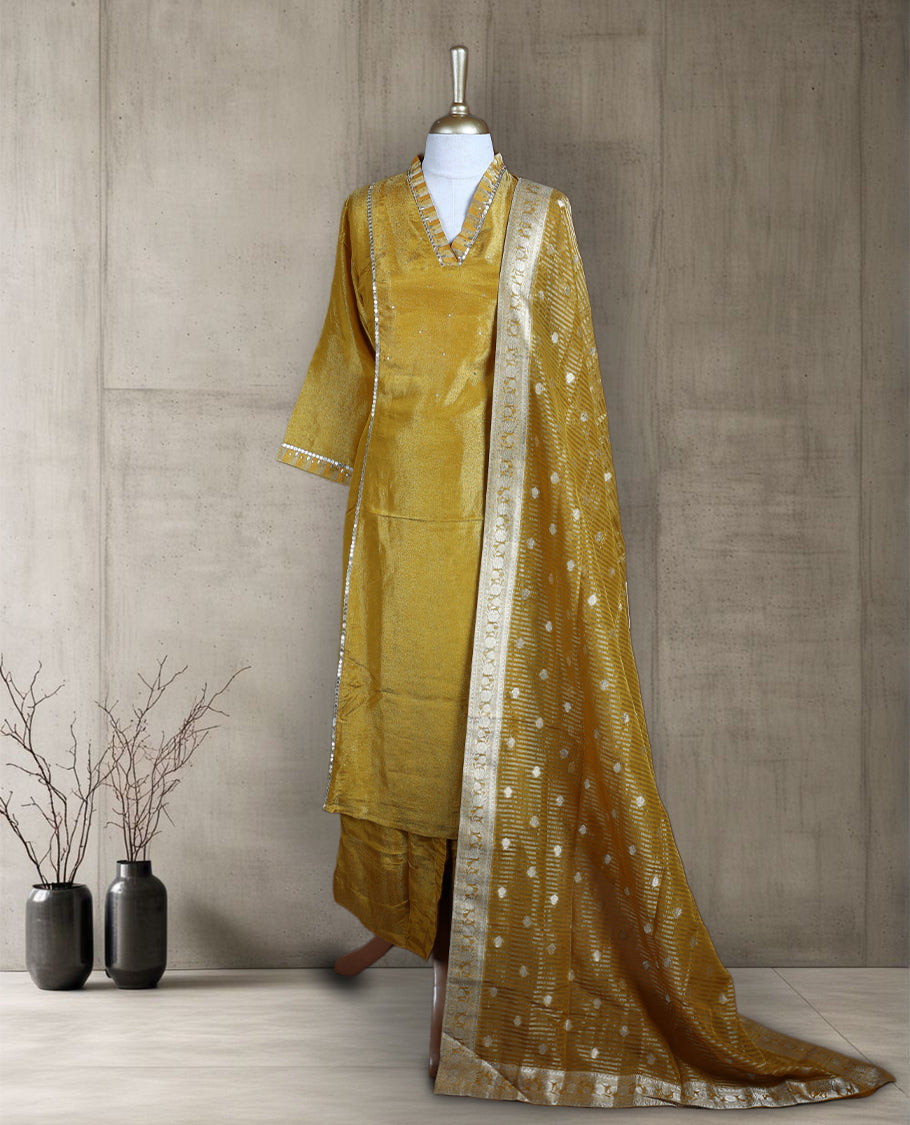 Golden yellow salwar from TWARA, featuring a V neck with delicate sequin highlights and plain finish on the top, paired with a matching bottom and a rich Banarasi style dupatta adorned with zari motifs and a contrast border.