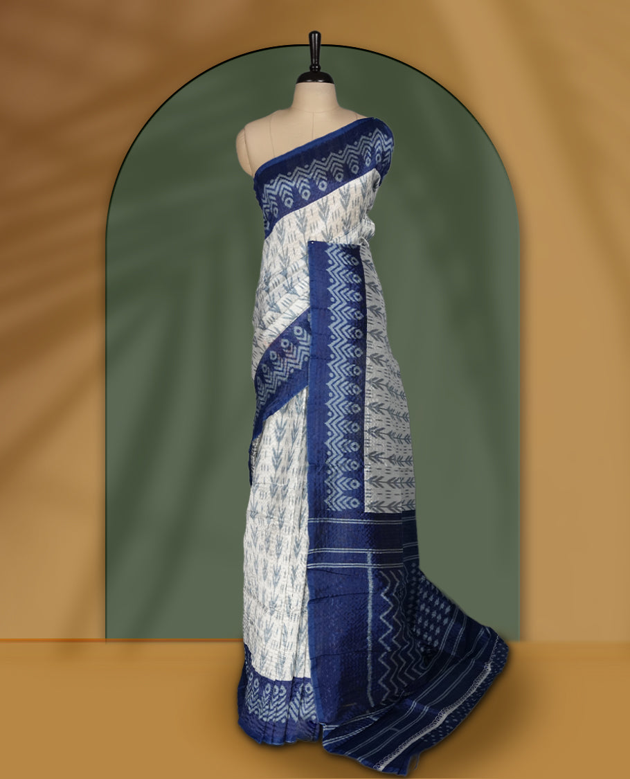 Classic off white colour saree adorned with intricate blue tribal motifs and rich woven patterns on the pallu and border & Paired with matching blouse.