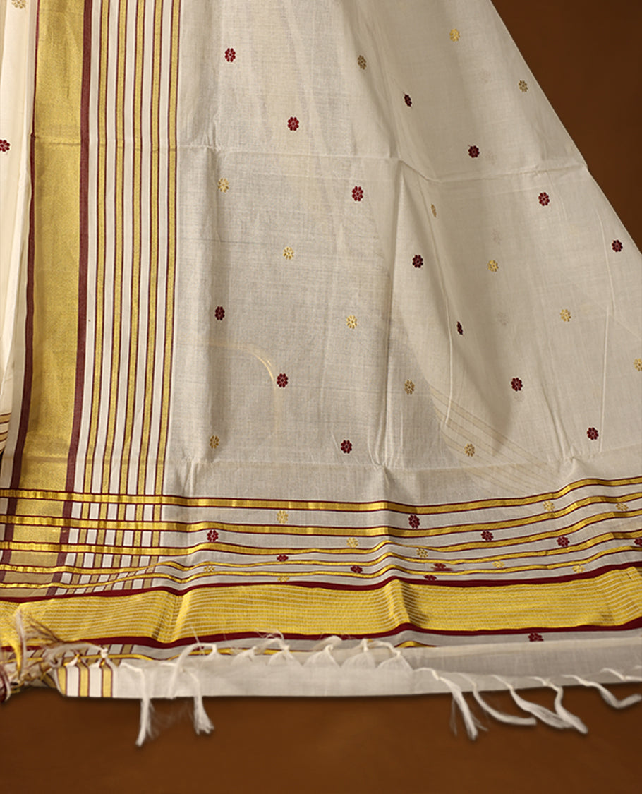 Off white colour pure handloom soft cotton kerala saree with maroon and mustard polka motifs, highlighted by a golden zari border and striped pallu in gold, maroon, and green, and paired with a matching blouse, perfect for festivities.