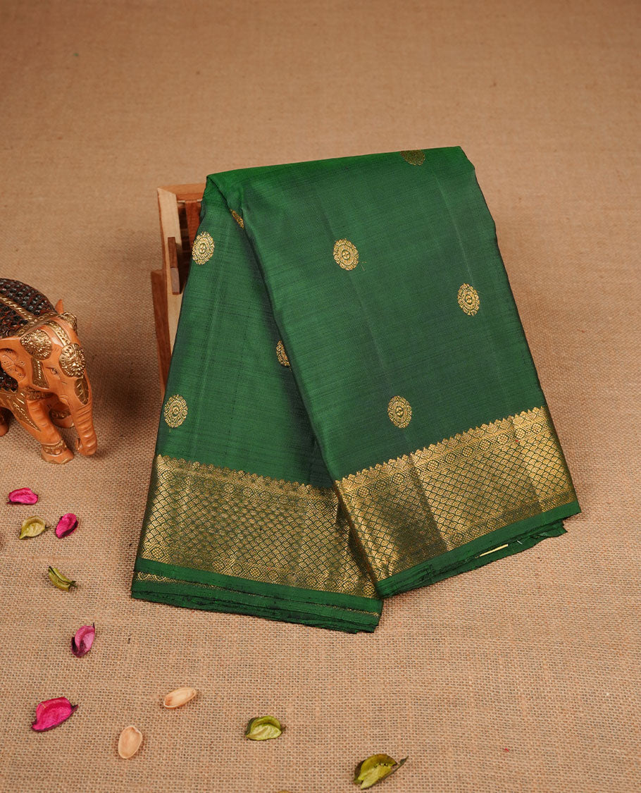 Bottle green pure traditional Kancheepuram silk saree adorned with gold zari chakra motifs across the body, featuring elegant gold zari traditional borders, beautifully paired with a matching blouse piece.