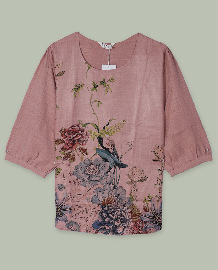Dusty rose round-neck top with three-quarter sleeves and placement floral print in muted blue, green, and burgundy tones along the front hem and side.