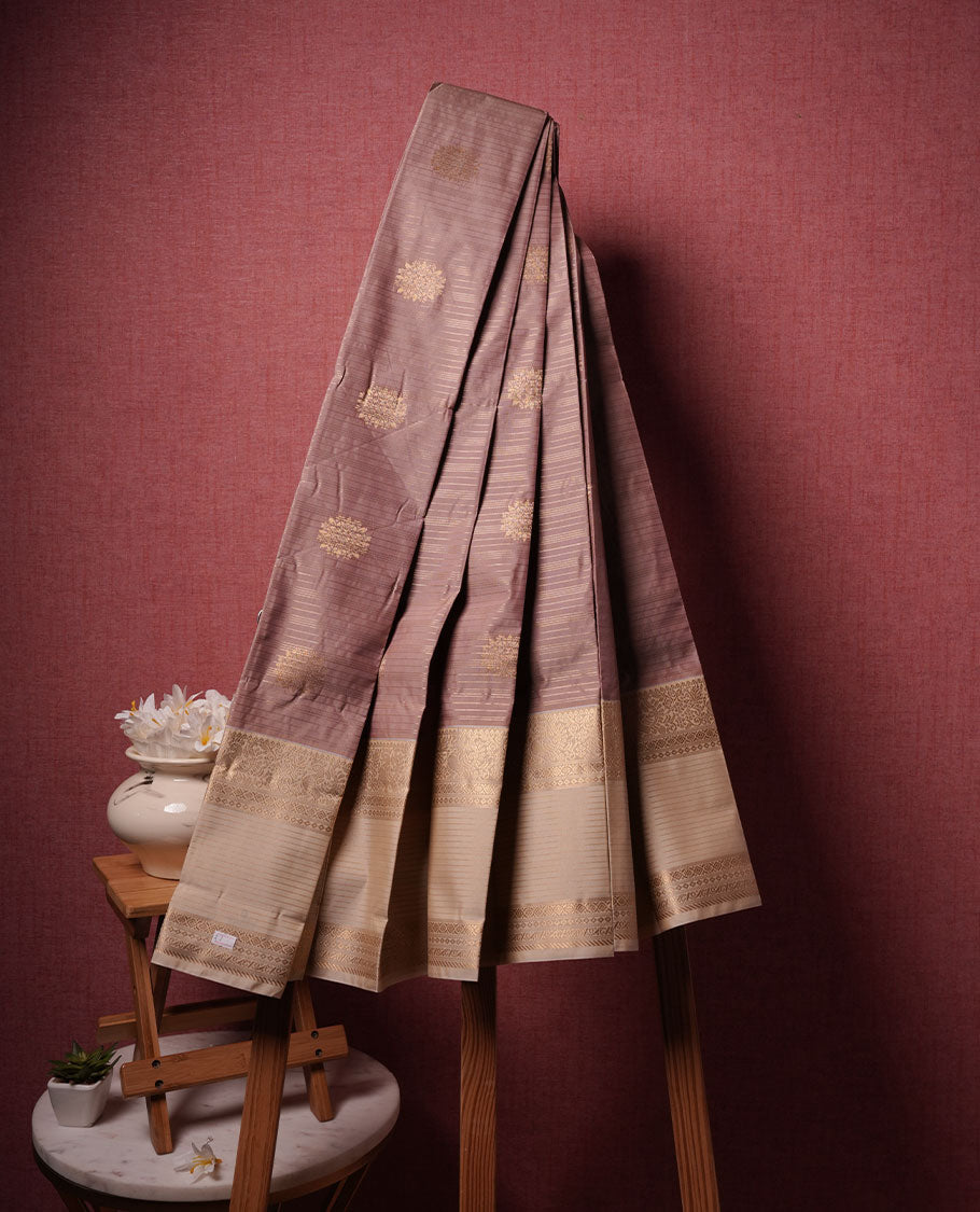 Nude brown colour semi silk saree highlighting gold zari strip pattern and motifs across body, featuring contrast cream colour border with gold zari pattern, comes with matching blouse .