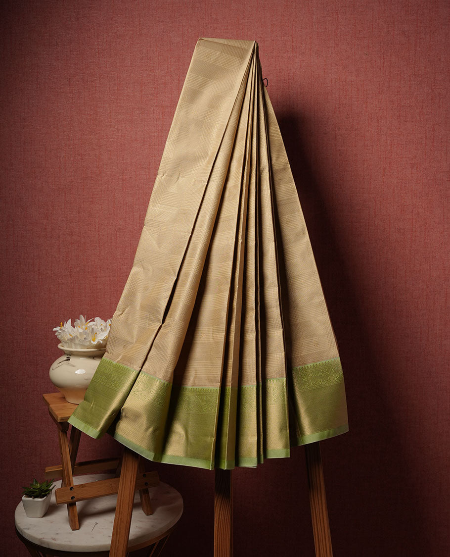 Beige colour semi silk saree highlighting gold zari check pattern and motifs across body, featuring contrast pastel green colour border with gold zari pattern, comes with matching blouse .