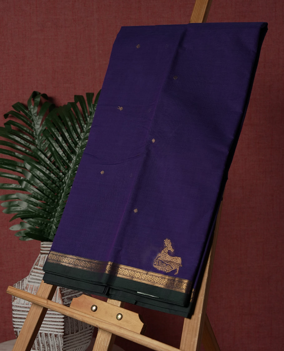 Purple colour pure Kanchi cotton saree embellished with delicate golden buttas and a graceful zari deer motif, paired with an intricately woven gold border, radiating elegance and tradition & Comes with matching blouse.