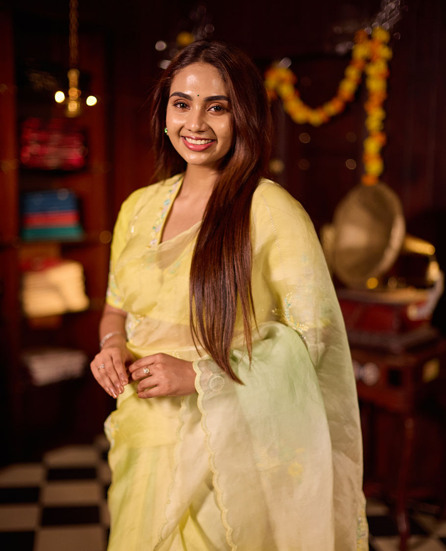 Pastel yellow colour premium organza saree featuring delicate floral hand embroidery with beads and sequins, finished with an elegant scalloped border and paired with a matching embroidered blouse.