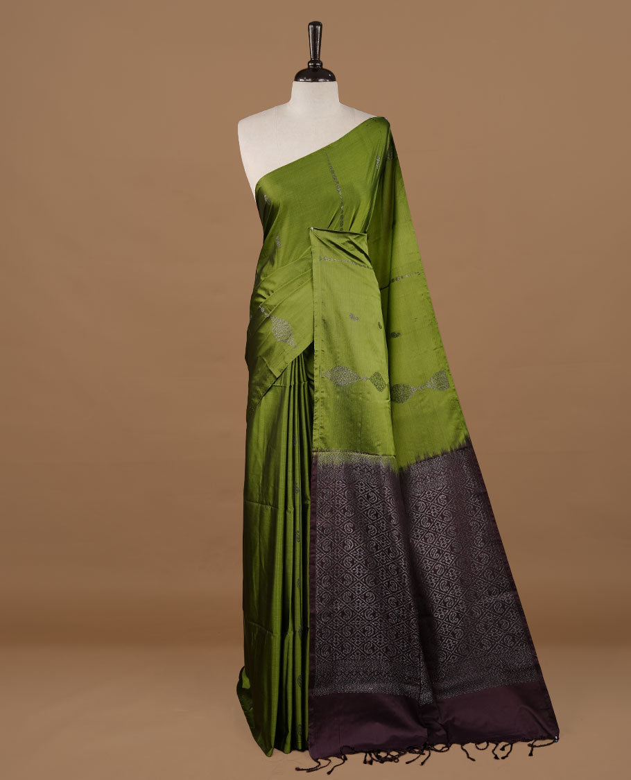 Olive colour soft silk saree features a sleek borderless design with intricate antique zari motifs, flowing into a striking contrast deep purple pallu and a matching blouse piece.