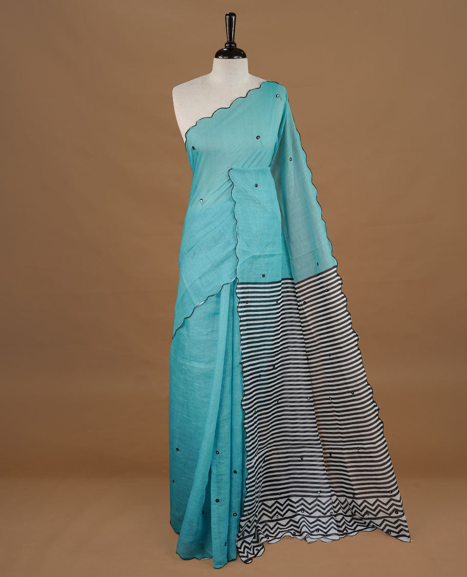 Aqua colour Semi Linen saree featuring mirror work with intricate thread detailing, enhanced by a stylish scallop border. Comes without a blouse piece.