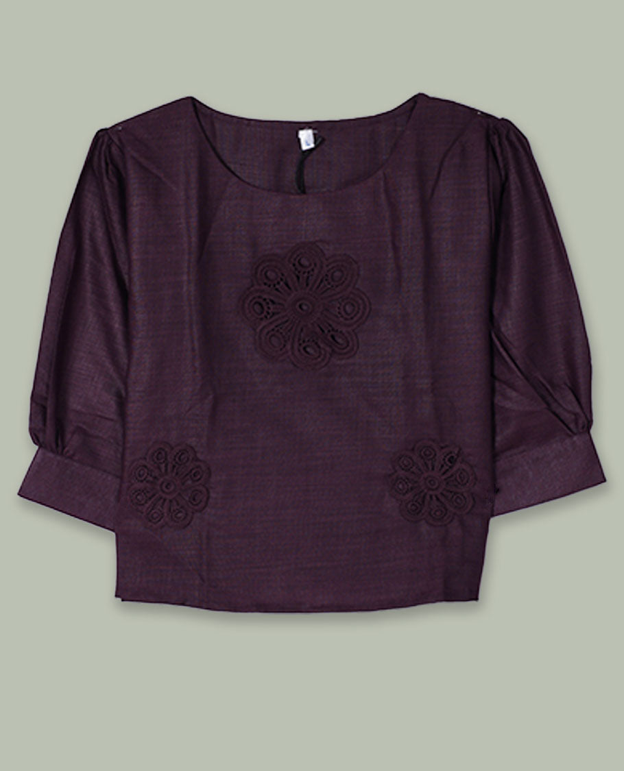 Deep plum three-quarter sleeve top with round neckline and tonal crochet floral appliqués placed at the center front and near the hem