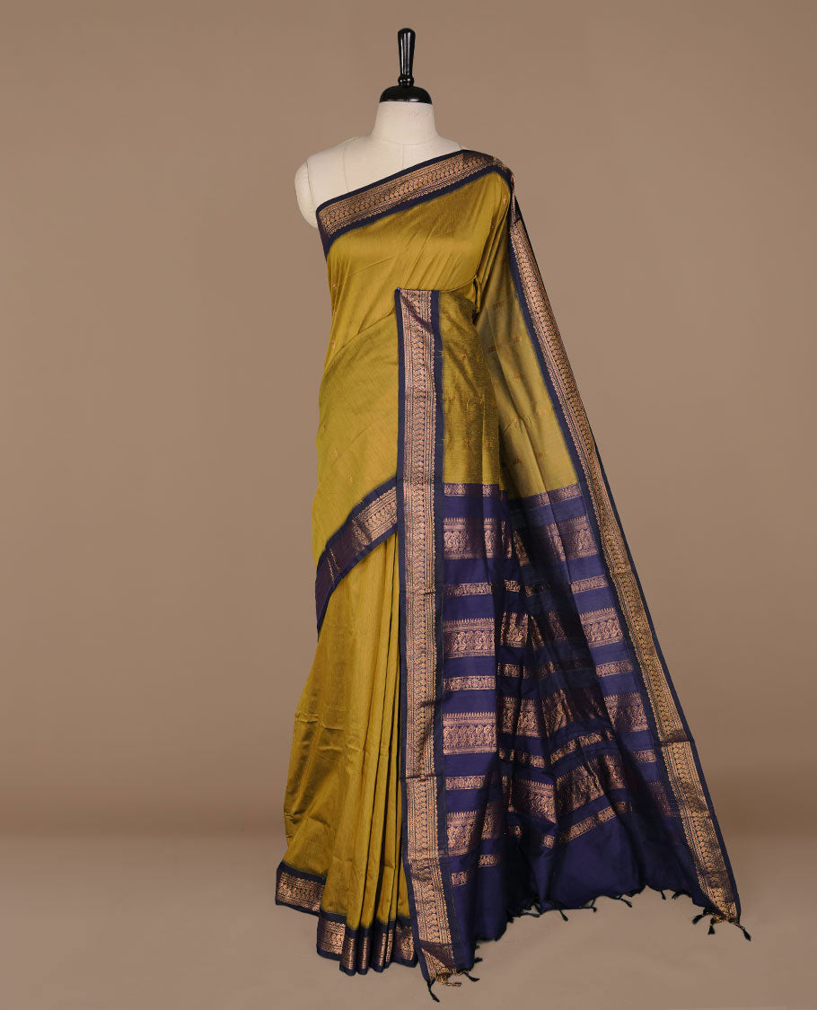 Olive colour kalyani cotton saree featuring antique zari motifs on body, complemented by Dark blue colour with Antique zari border, paired with matching blouse piece.