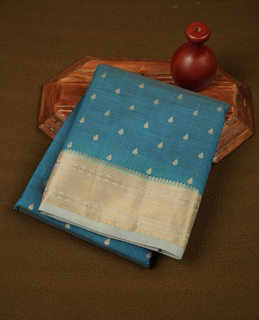 Teal colour semi tussar saree featuring gold zari buttas across body, contrast grey colour gold zari border and comes with matching blouse piece.