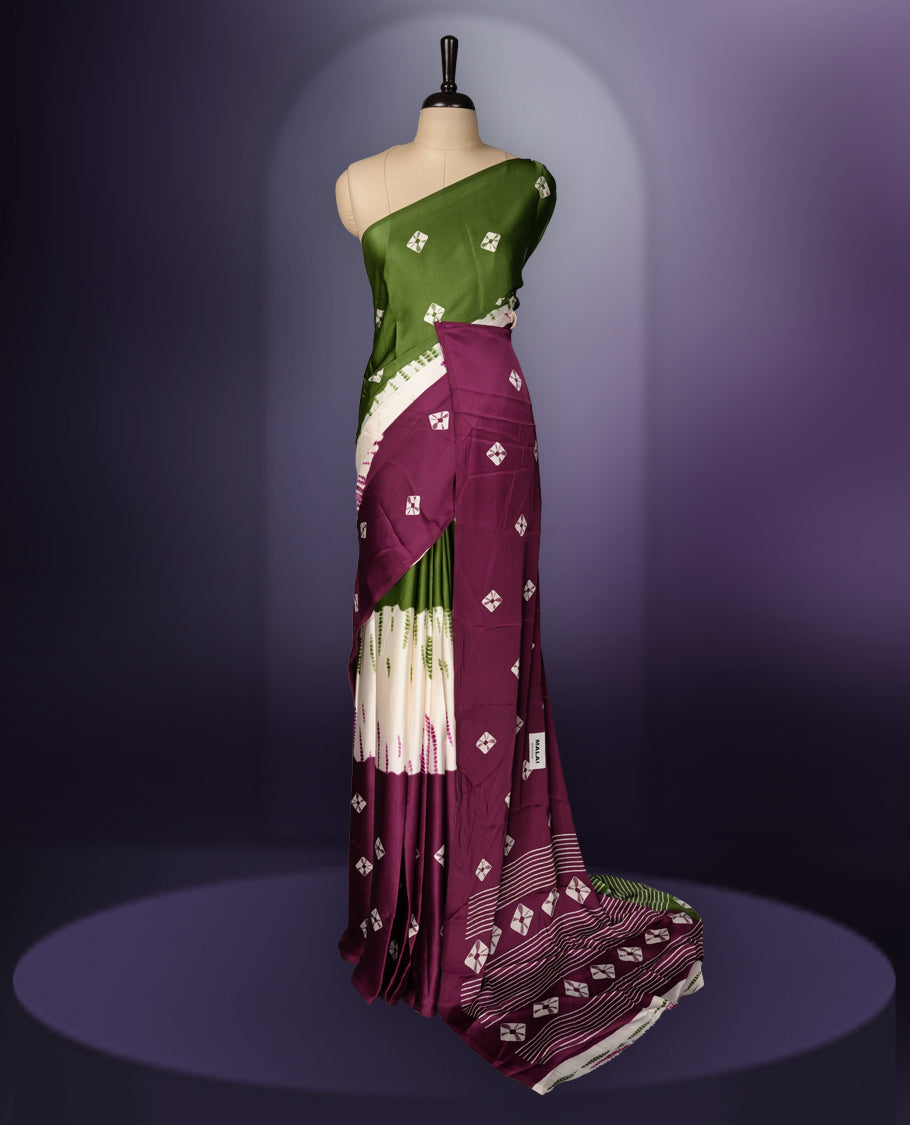 Rich green and purple saree adorned with small woven motifs on the body, enhanced by a contrast border, complemented with a traditional patterned pallu, and paired with a matching blouse.