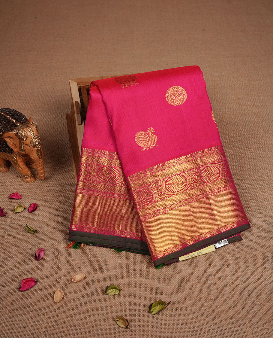 Rani pink colour pure traditional Kancheepuram silk saree adorned with gold zari peacock & chakra motifs across the body, featuring elegant traditional borders, beautifully paired with a matching blouse piece.