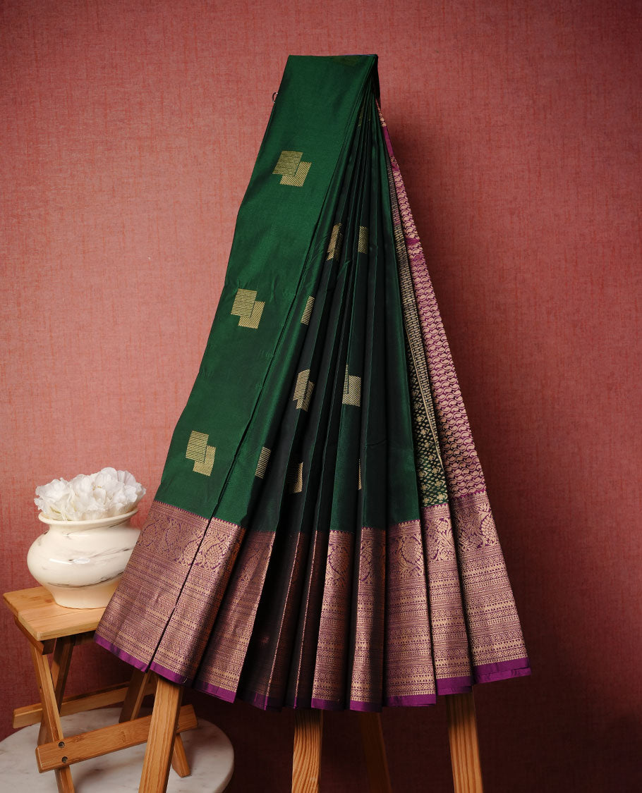 Green colour soft silk saree featuring Gold zari motifs on body, complemented by contrast purple colour with traditional border, paired with matching blouse piece.