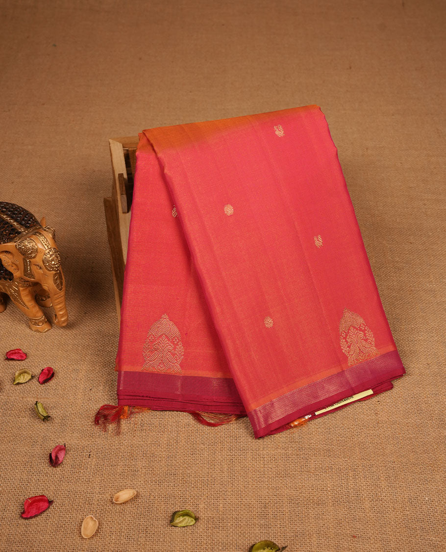 Orange and pink double shade pure traditional Kancheepuram silk saree adorned with elegant zari peacock and chakra motifs on the body, complemented by a simple contrast zari woven border, paired with a matching blouse piece.