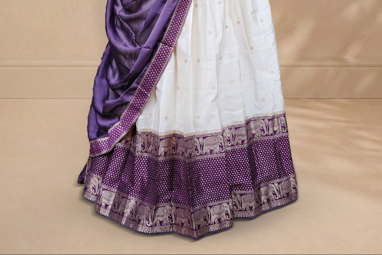 Cream colour Half saree featuring Gold zari buttas on skirt with Zari border on contrast Purple colour border, Unstitched Blouse and matching dupatta.