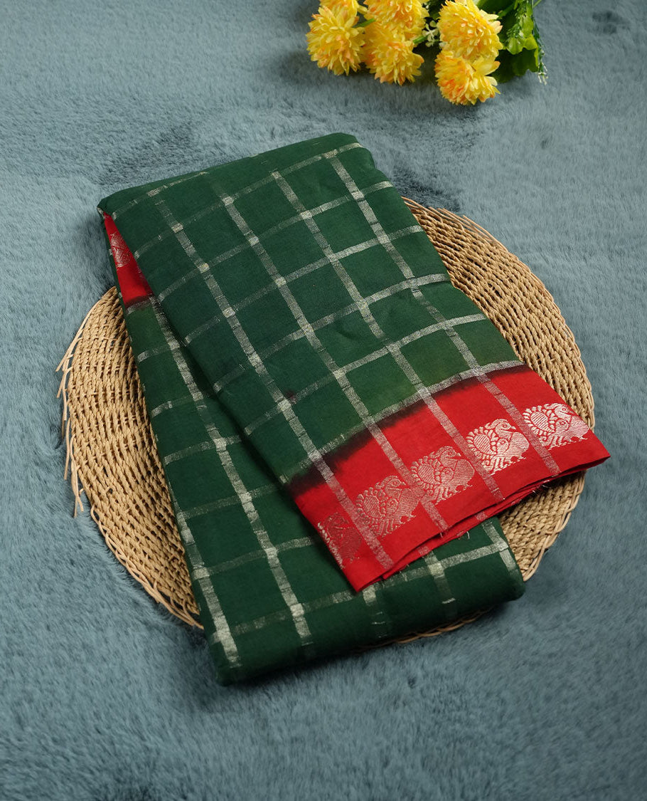 Bottle green colour chettinad cotton saree with silver zari checkered pattern on the body, paired with a contrast red colour pallu featuring silver zari floral border, and a coordinated red checkered blouse piece with matching silver zari border.