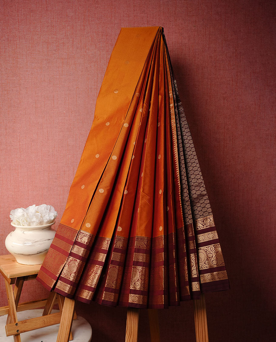 Burnt mustard colour soft silk sareee featuring gold zari Motifs on body, complemented by contrast Maroon colour with zari border, paired with matching blouse piece.