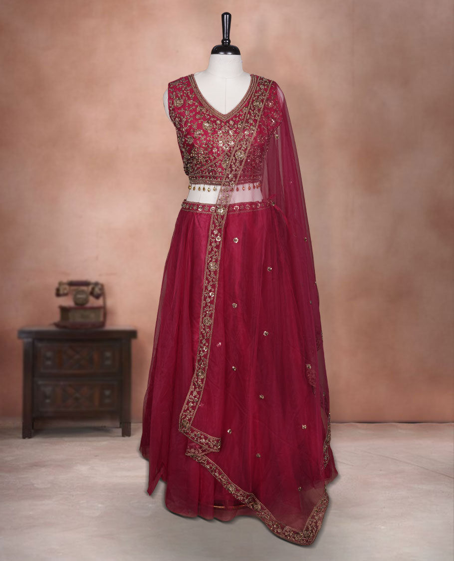 Maroon colour lehenga set with stitched sleeveless Antique thread embroidered & beats worked blouse featuring sheer neckline, matching stitched flared lehenga, and plain sheer dupatta.