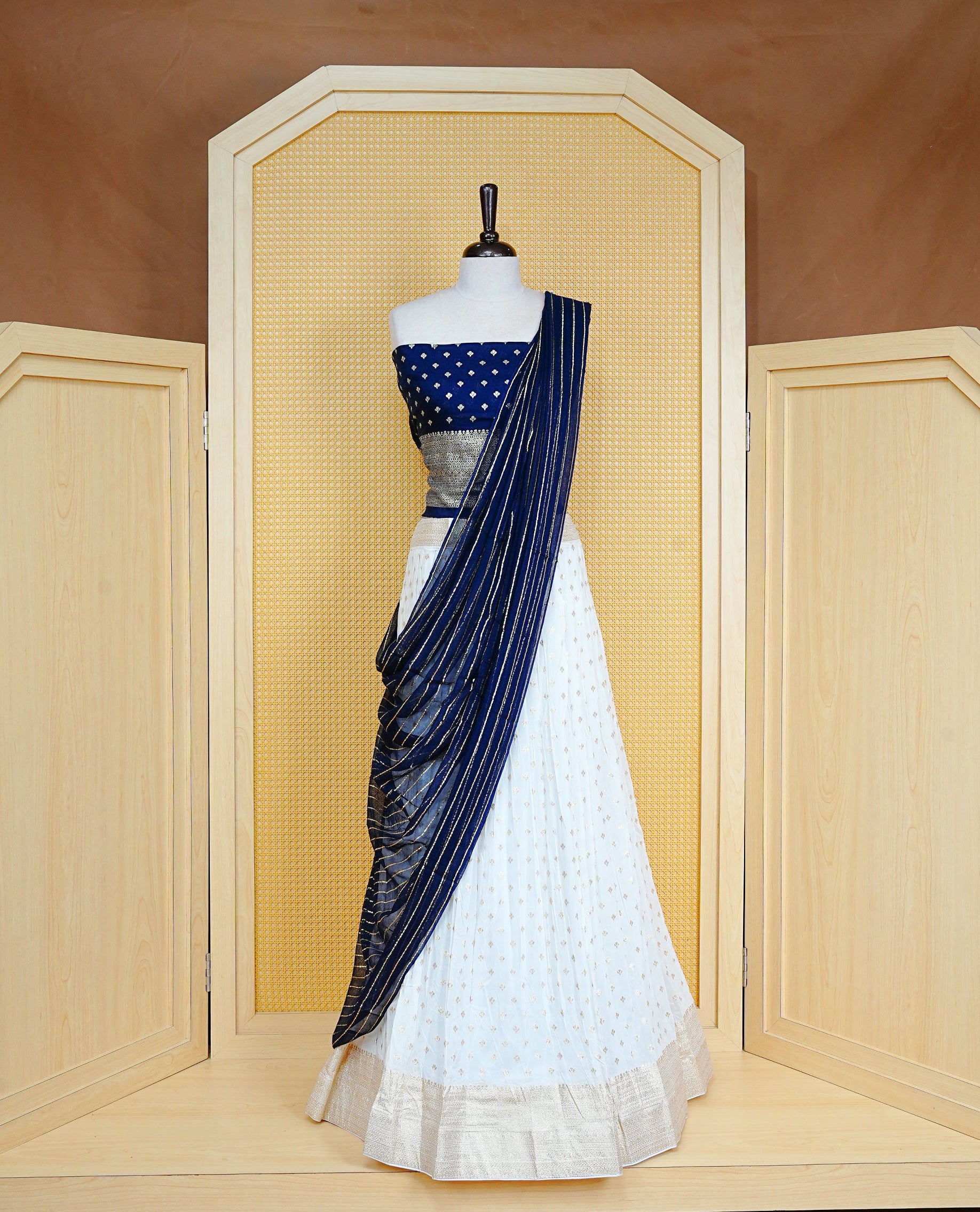 Cream colour Semi Stitched Dhavani Set Cream colour Skirt With Floral Motifs on Border, Paired with Contrast Navy Blue colour With Gold zari motifs on Unstitched Blouse, Elegant Dupatta For Prefect look.