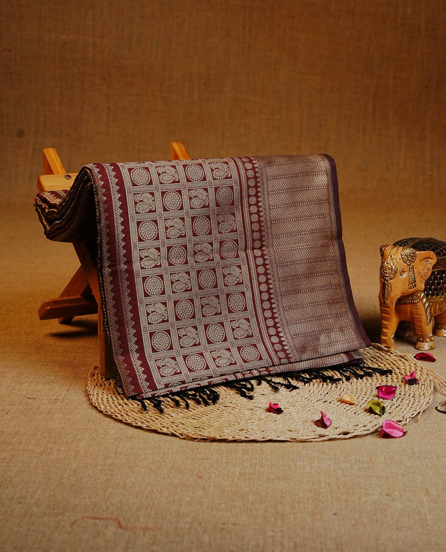 Chocolate brown color Semi Soft Silk Saree Featuring Gold Zari Checks With Delicate Motifs And Stripes Across The Body, Enhanced With A Self Coloured Gold Zari Border, And Paired With A Matching Blouse Piece.