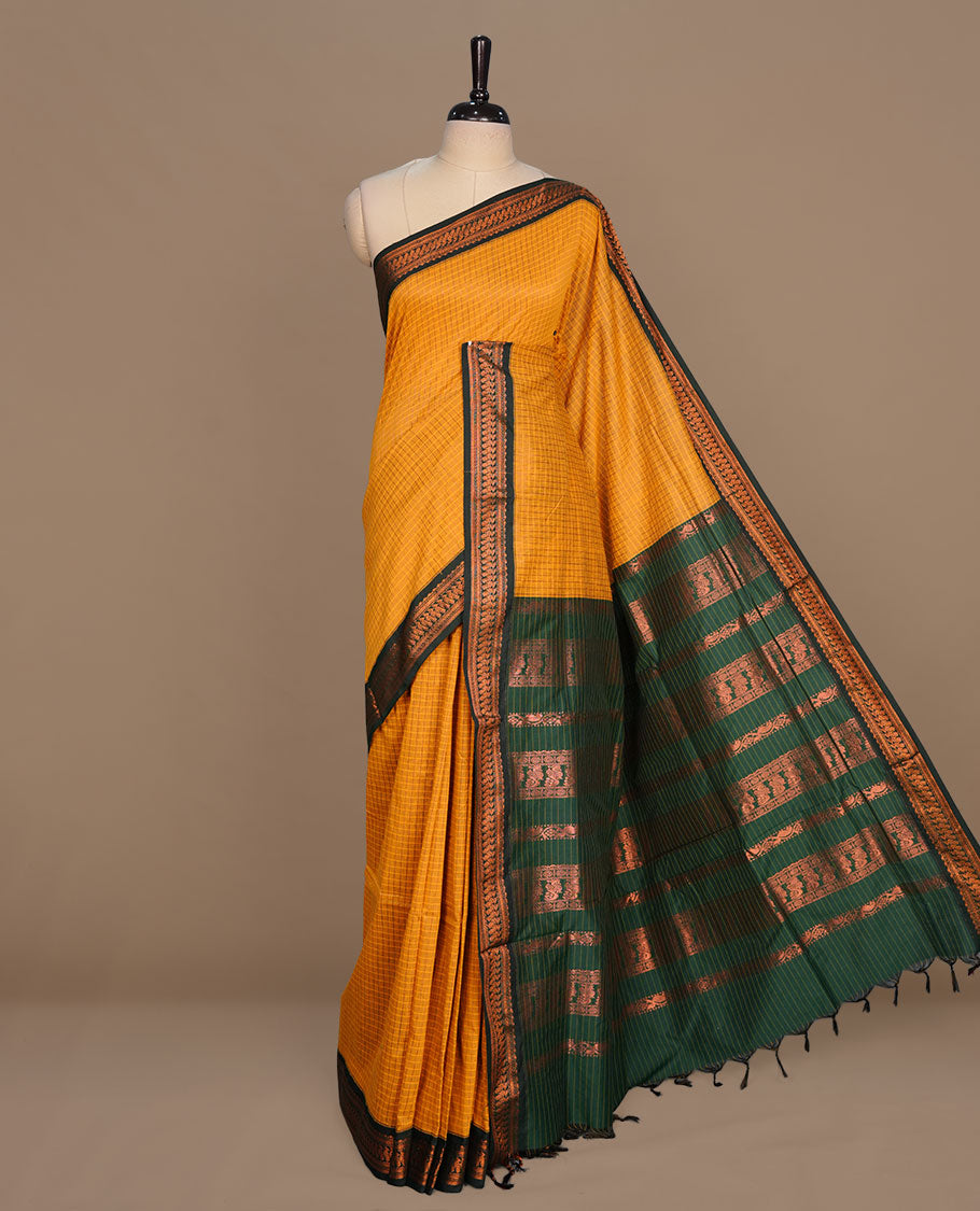 Mustard colour kalyani cotton saree featuring gold zari motifs on body, complemented by contrast green color with copper zari pattern border , paired with matching blouse piece.