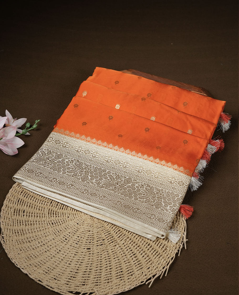 Orange colour banaras satin crepe saree featuring gold zari motifs on body, with contrast cream colour border with gold zari pattern and paired with matching blouse.