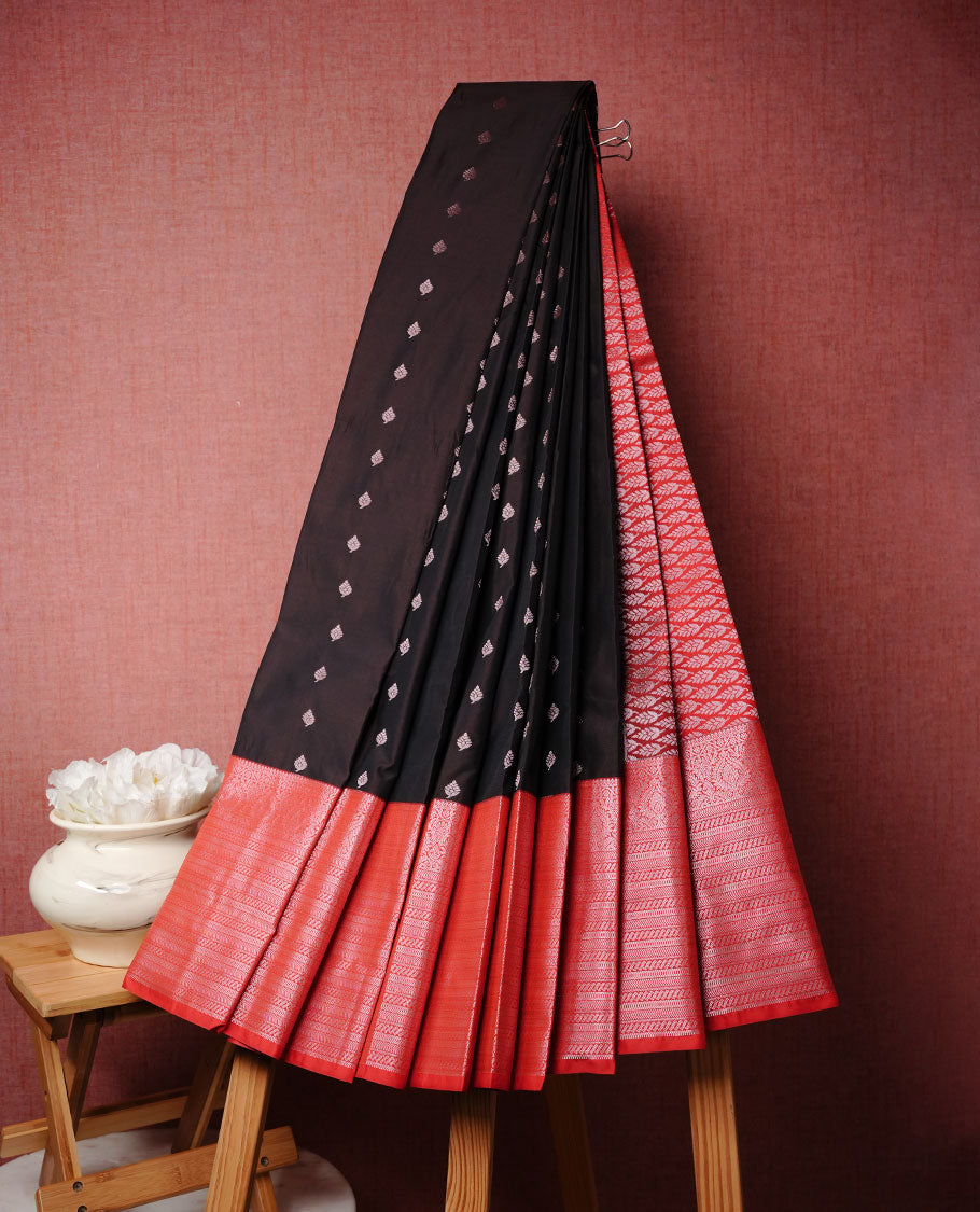 Black colour soft silk sareee featuring gold zari motifs on body, complemented by contrast Red colour with zari border, paired with matching blouse piece.