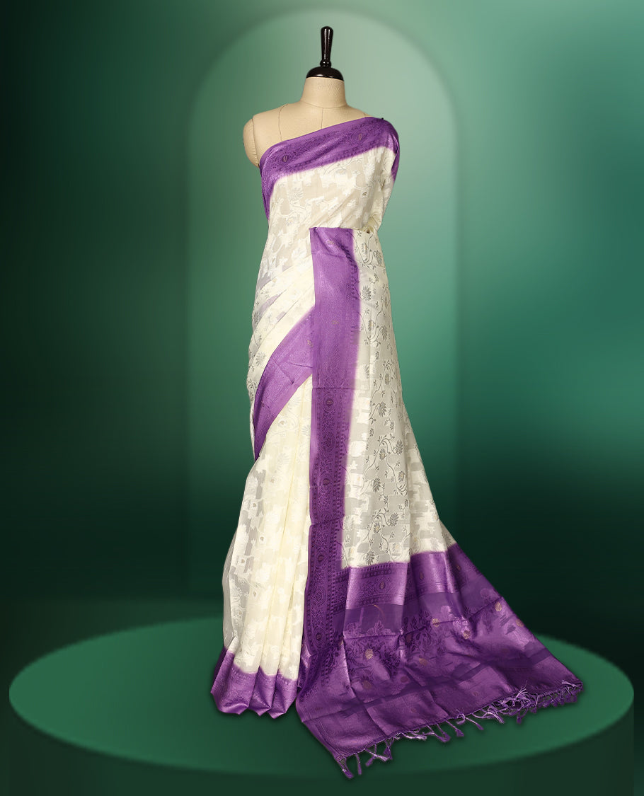 White colour saree adorned with delicate self woven motifs across the body, highlighted with a striking Purple woven border and pallu, finished with tassels, and paired with a matching blouse