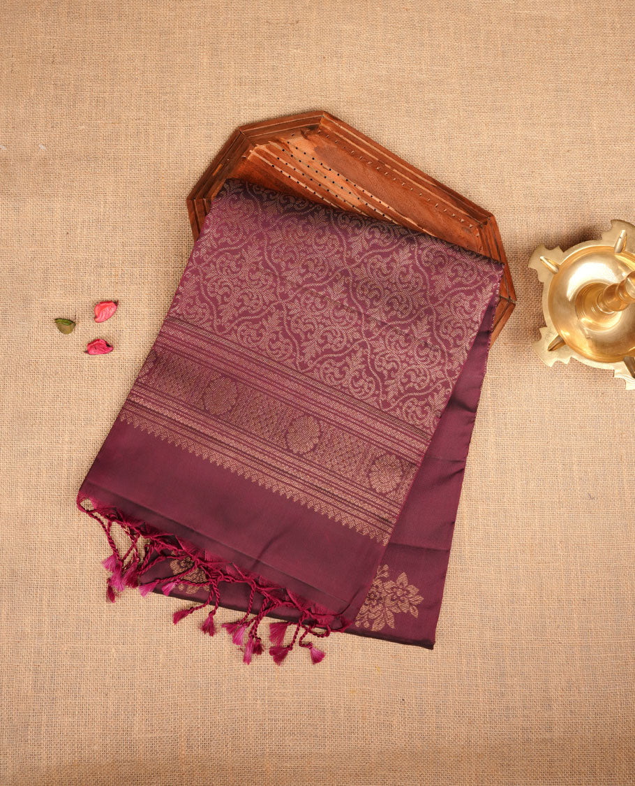 Burgundy colour soft silk saree featuring gold zari motifs on body, complemented by self colour with traditional border with tassel at pallu, paired with matching blouse piece.