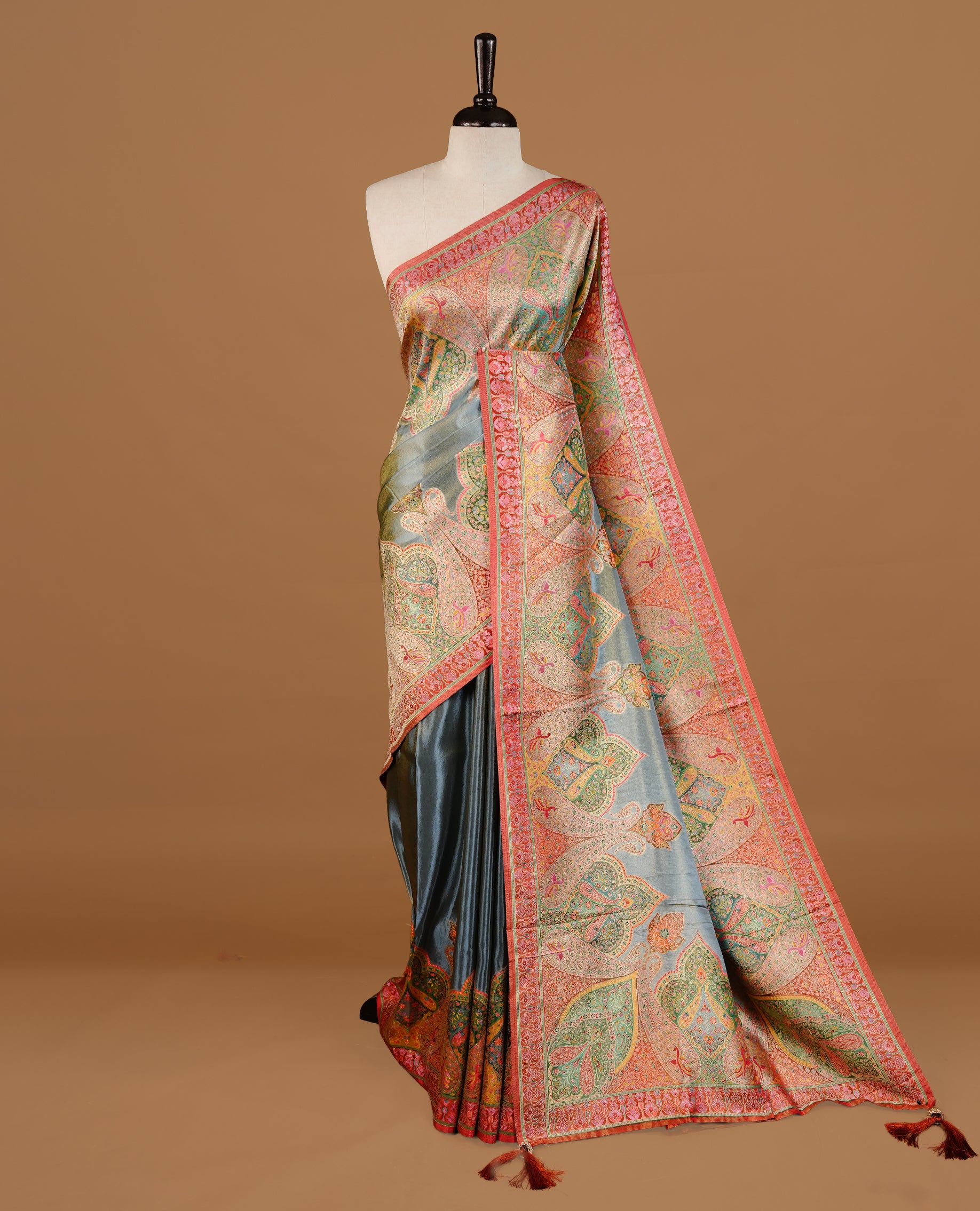 Grey colour Pashmina Saree featuring a plain lustrous body, a multicolour traditional woven border, a rich traditional woven pallu with intricate paisley motifs, paired with a matching grey blouse.