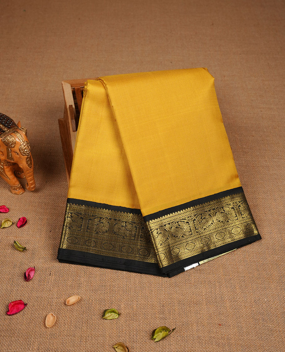 Mustard yellow colour pure traditional Kancheepuram silk saree featuring elegant contrast black zari traditional borders, beautifully paired with a matching blouse piece.