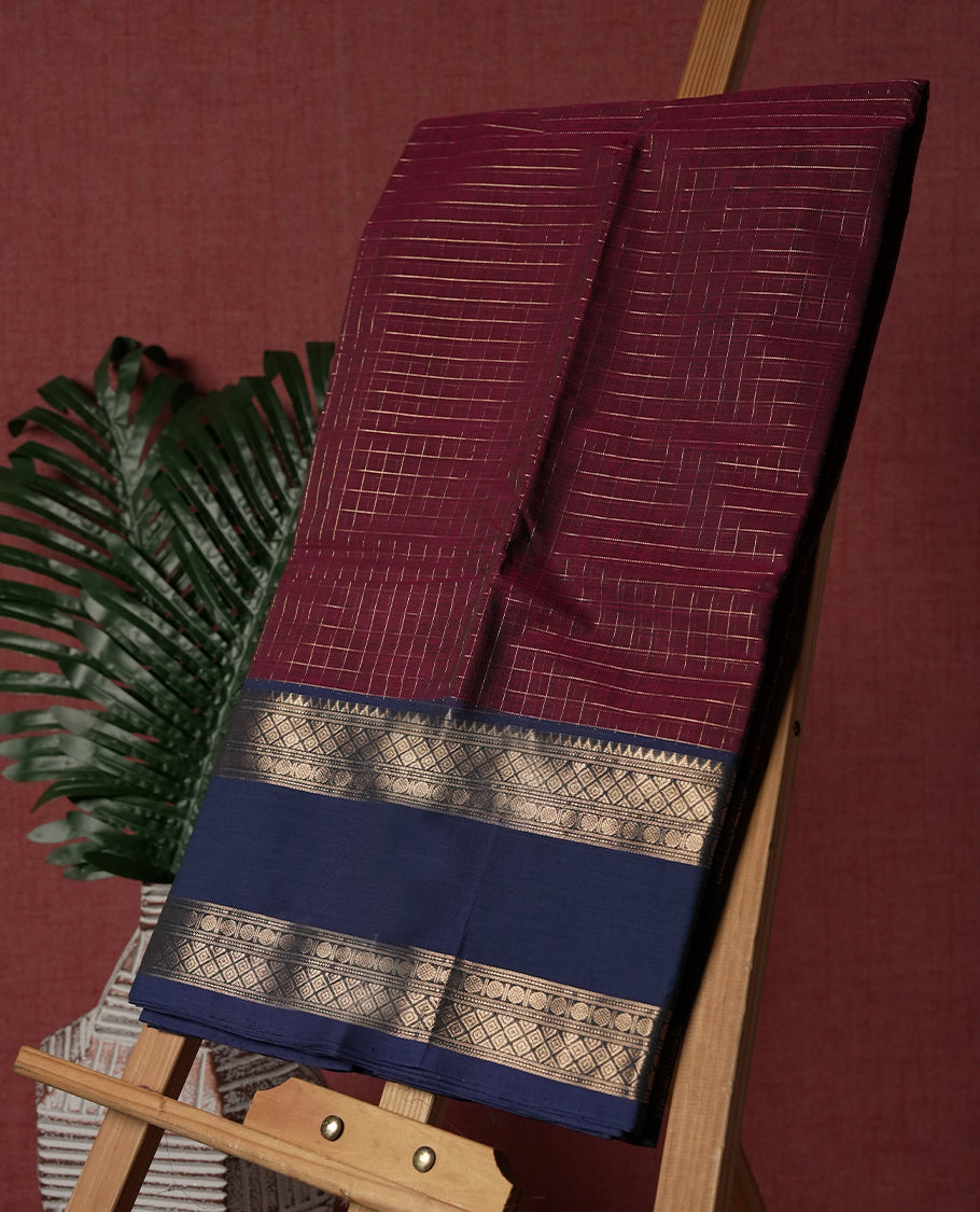 Maroon colour pure Kanchi cotton saree featuring with delicate golden checks on body, paired with a contrasting navy blue zari woven border & Includes a matching blouse piece for a complete look.