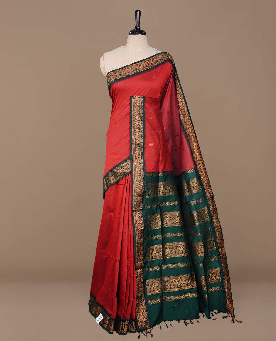 Red colour kalyani cotton saree featuring antique zari motifs on body, complemented by Green colour with Antique zari border, paired with matching blouse piece.