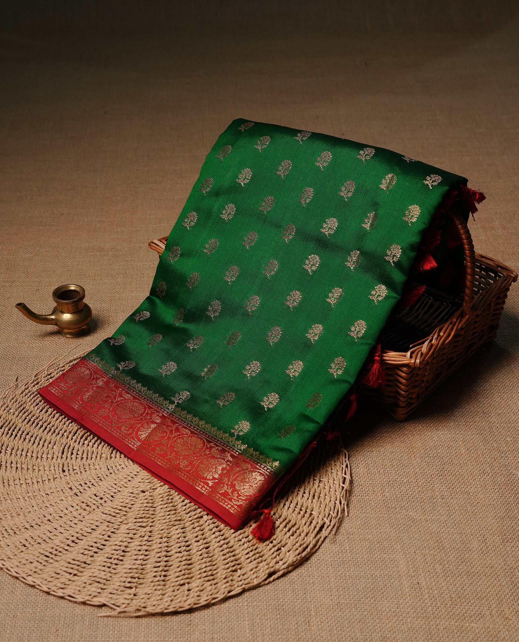Green colour Banaras tussar silk saree featuring elegant gold zari buttas across the body, complemented by a contrast Red border with rich zari detailing. Comes paired with a matching blouse piece.