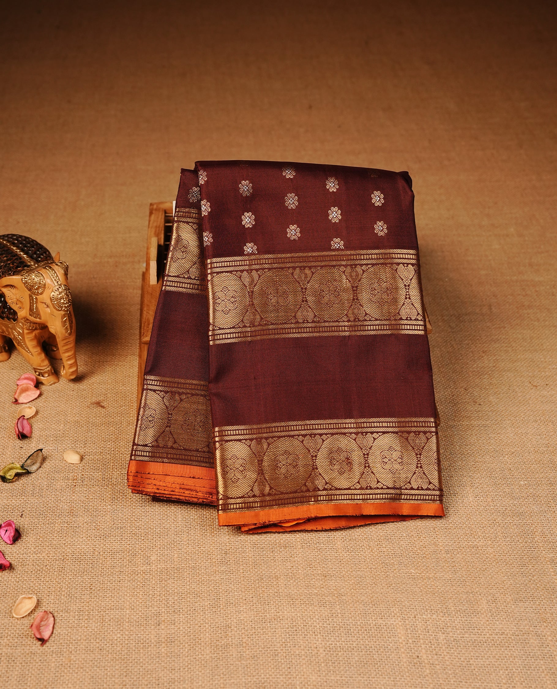 Chocolate colour Kancheepuram silk saree featuring Gold & silver Floral Pattern onbody, Highlighting Gold Zari border with Orange piping, paired with matching blouse piece.