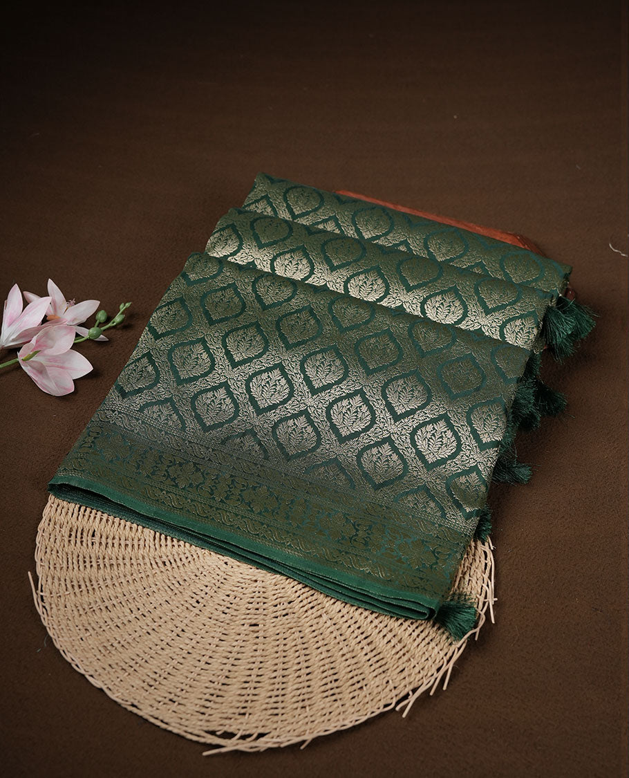 Dark green colour banaras satin crepe saree featuring gold zari pattern across body, with self colour border with gold zari pattern and paired with matching blouse.